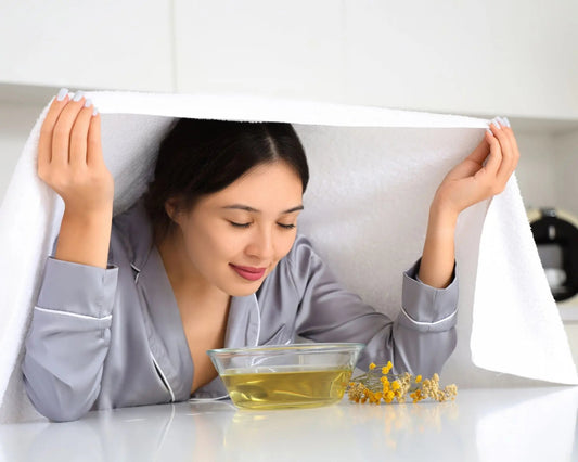 Femme réalisant une inhalation, tête couverte d'une serviette, respirant profondément pour soulager ses voies respiratoires.