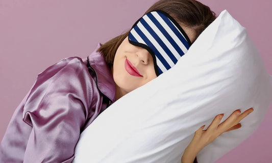 Femme portant un masque de sommeil, tenant un oreiller dans ses bras avec une expression apaisée.