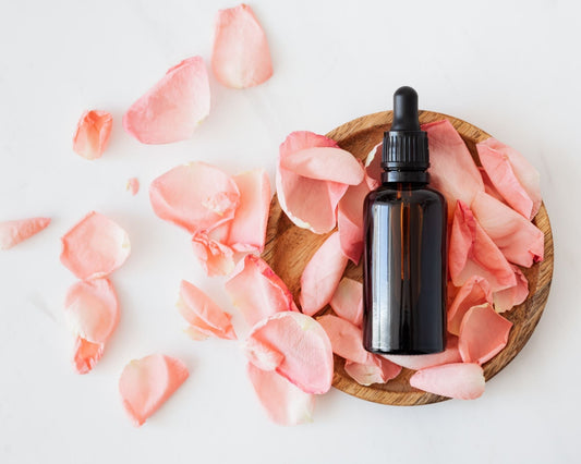 Flacon de cosmétique naturelle avec pétales de rose roses posé sur une assiette en bois, concept de soin de la peau naturel et floral