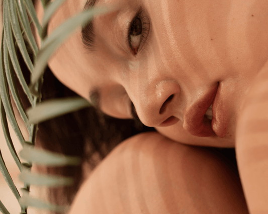 femme dans l'ombre d'une plante, visage sur le genou