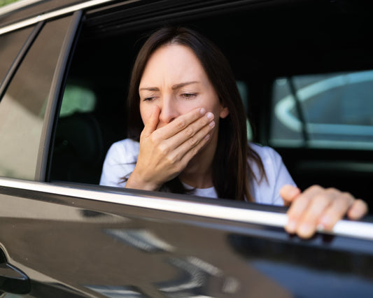 Femme souffrant de nausées en voiture, regardant par la fenêtre avec la main sur la bouche – symptôme typique du mal des transports