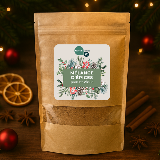 Sachet du mélange d’épices pour vin chaud MerveilleNature posé sur une table festive, entouré de cannelle, clous de girofle, gingembre et écorces d’orange, avec un sapin de Noël et des boules décoratives en arrière-plan, créant une ambiance hivernale chaleureuse et gourmande.
