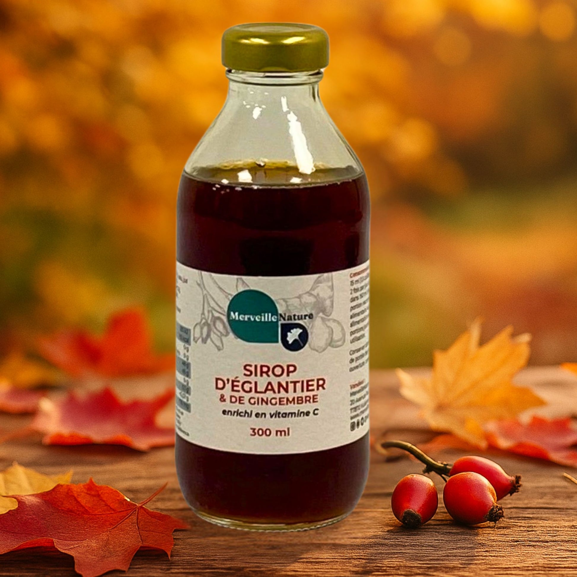 Bouteille de sirop naturel immunité à l’églantier, gingembre et vitamine C, posée sur une table en bois, accompagnée de cynorrhodons frais dans un décor automnal aux feuilles multicolores
