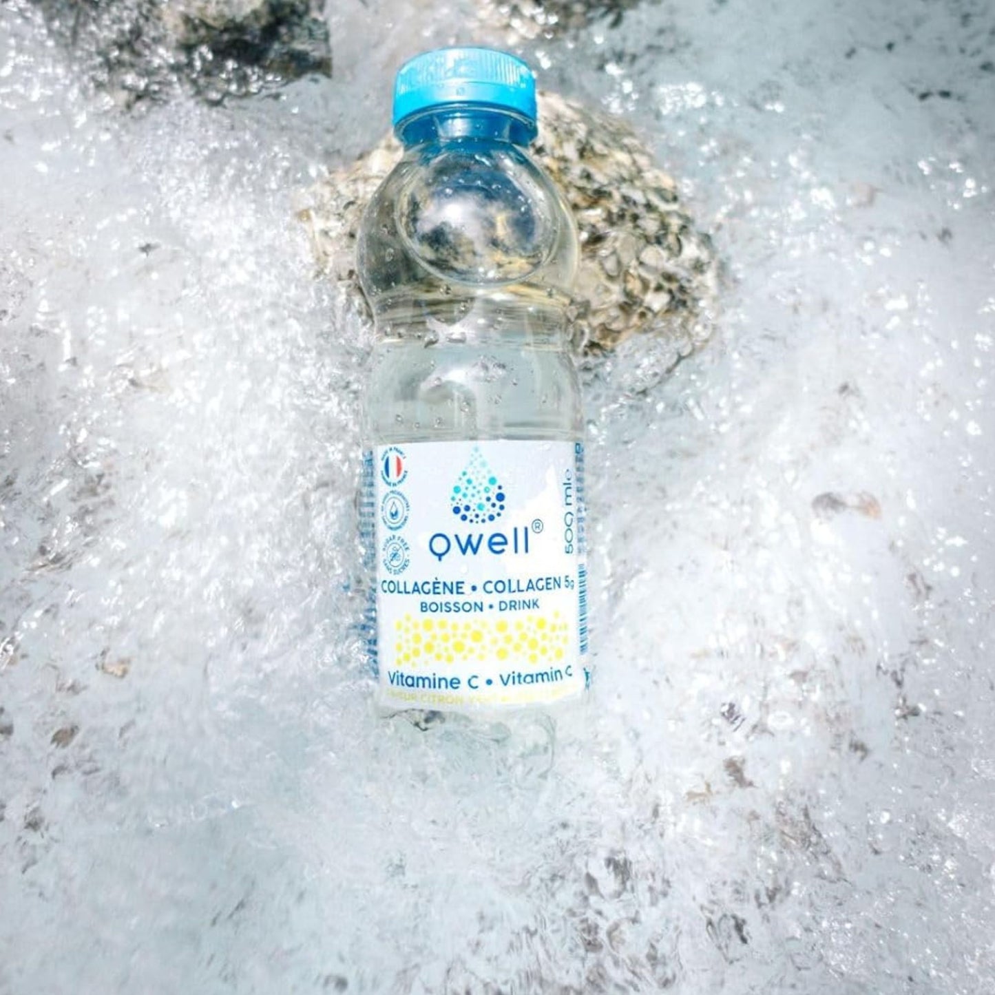 Bouteille Qwell collagène saveur citron vert enrichie en vitamine C, posée dans de l'eau vive et des rochers, symbolisant fraîcheur, pureté et hydratation naturelle optimale