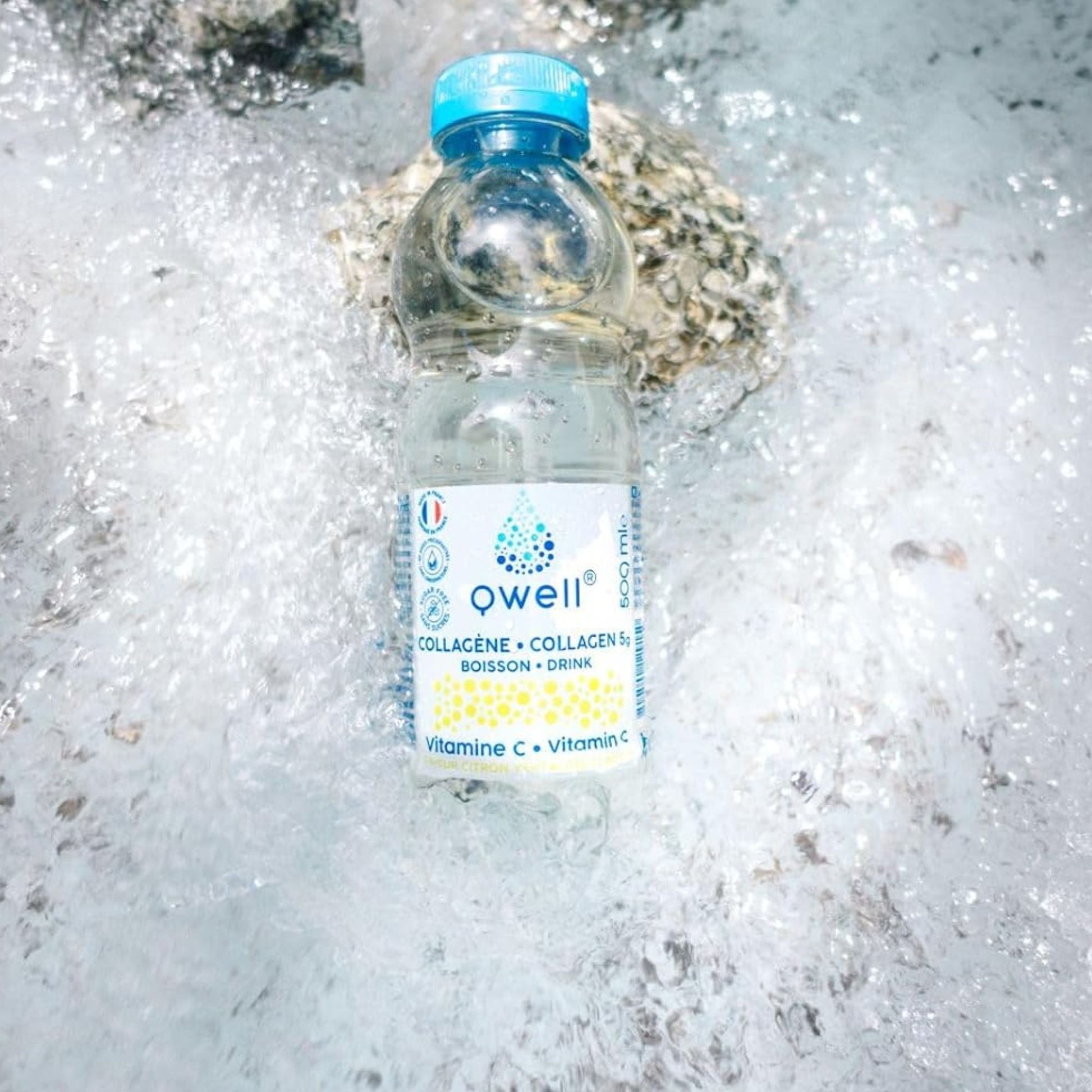 Bouteille Qwell collagène saveur citron vert enrichie en vitamine C, posée dans de l'eau vive et des rochers, symbolisant fraîcheur, pureté et hydratation naturelle optimale
