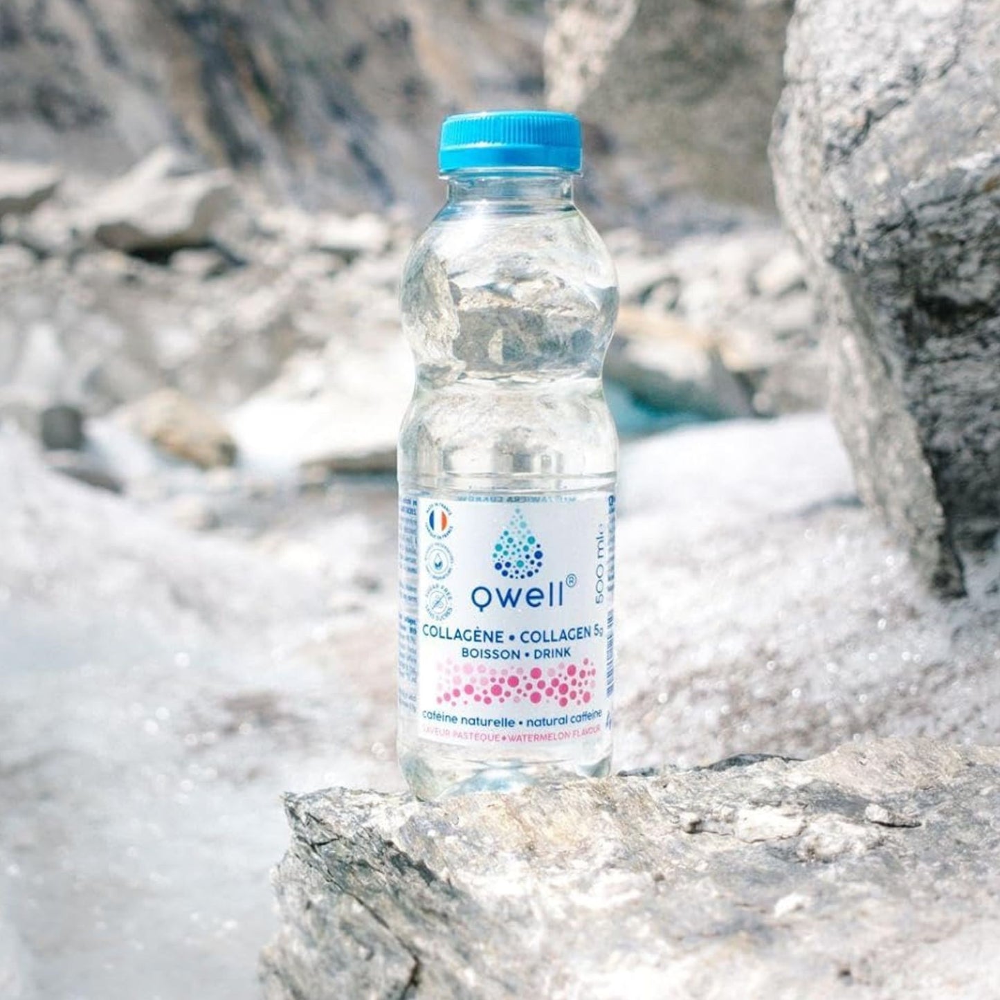 Bouteille Qwell collagène saveur pastèque avec caféine naturelle posée sur des rochers en montagne, évoquant vitalité et performance physique naturelle