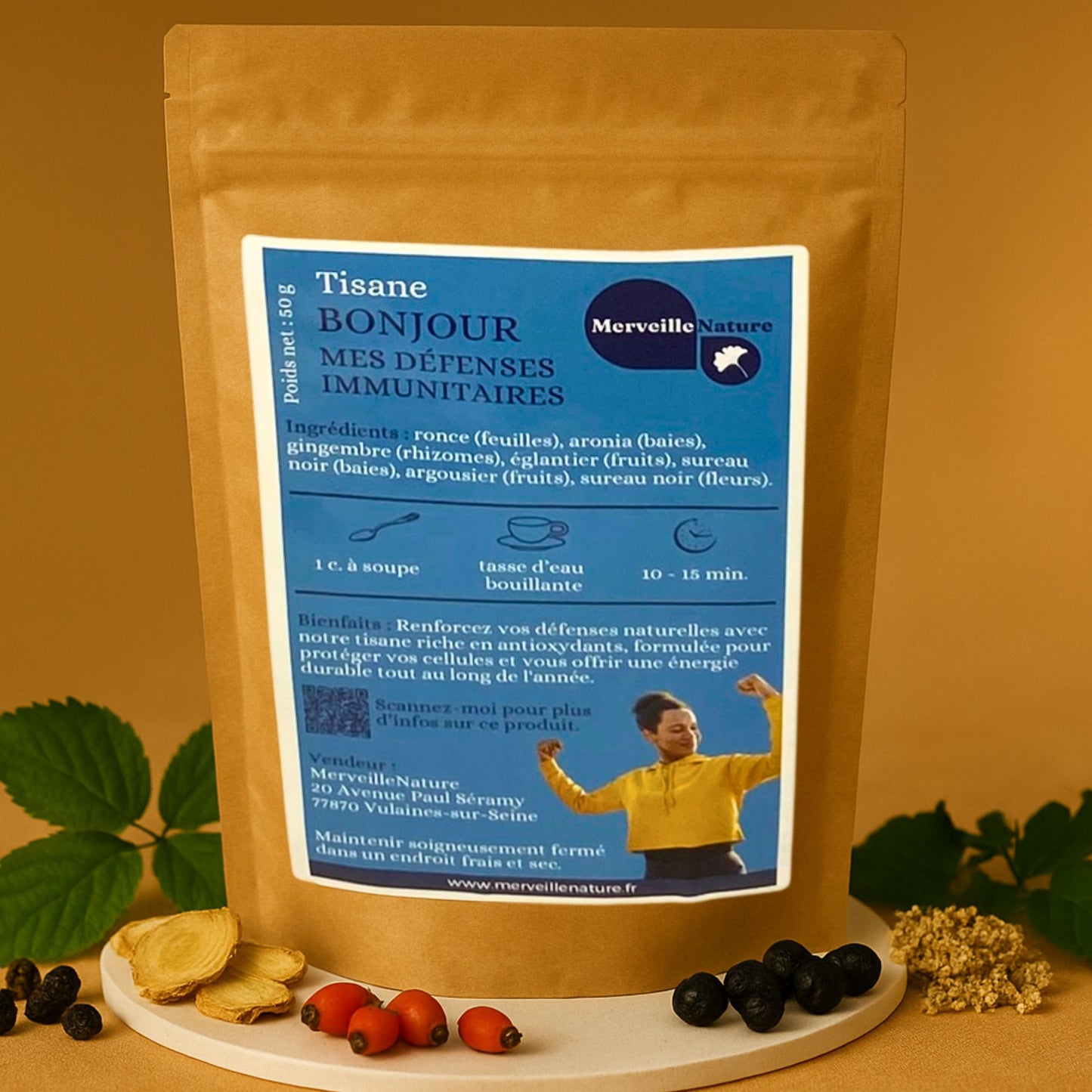 Sachet en kraft de la tisane ‘Bonjour Mes Défenses Immunitaires’ de MerveilleNature, avec étiquette bleue présentant la liste des ingrédients et conseils d’infusion, photographié sur un fond chaud avec des baies de sureau, cynorhodon, gingembre et feuilles disposées autour.
